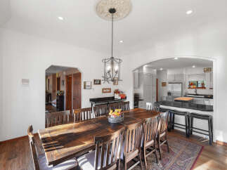 This spacious dining room features a large, rustic wooden table with seating for eight, perfect for family gatherings.