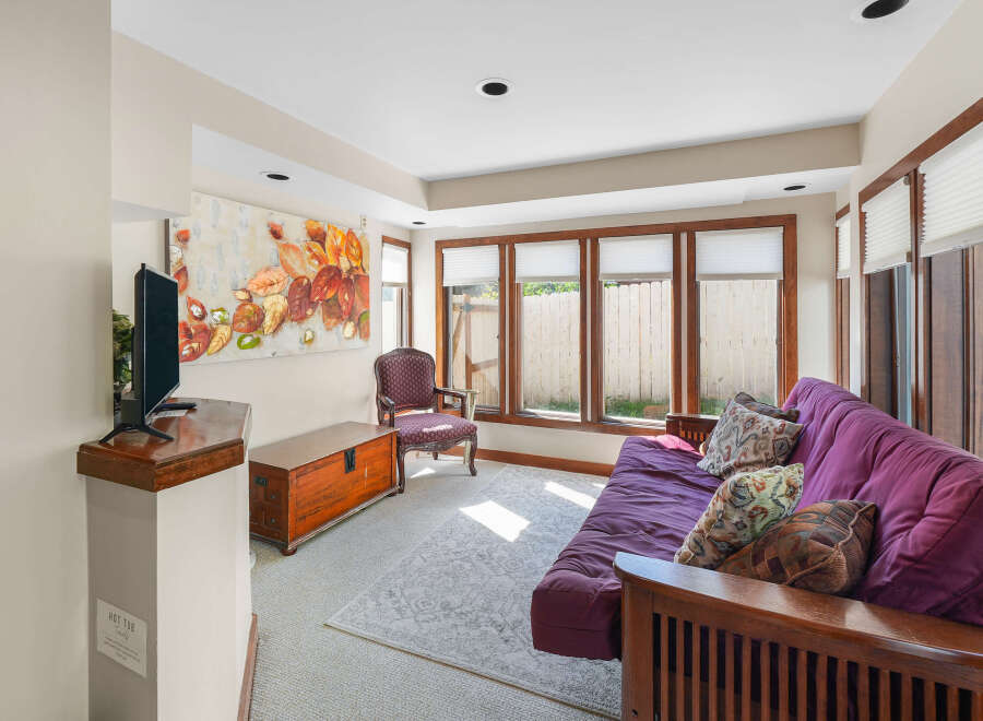 Relax and unwind in this inviting living space, featuring a comfortable purple futon sofa adorned with decorative pillows.