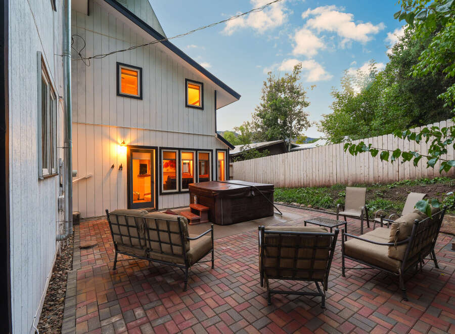 Enjoy outdoor living with this spacious patio featuring comfortable seating and a hot tub, perfect for relaxation and entertaining.