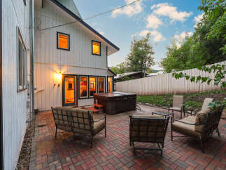 Enjoy outdoor living with this spacious patio featuring comfortable seating and a hot tub, perfect for relaxation and entertaining.