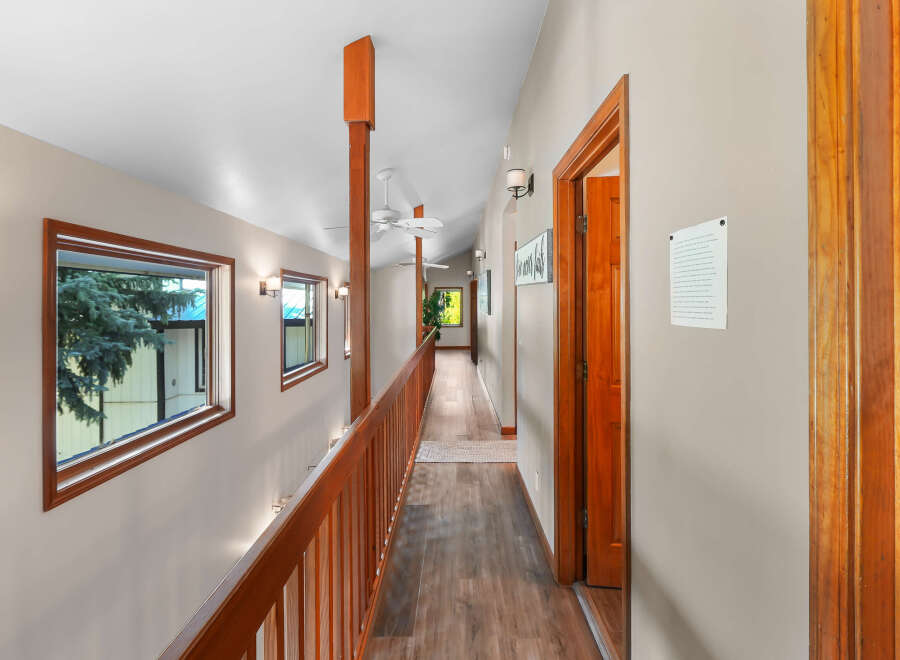 This spacious hallway features a warm wooden railing and a rich wood-paneled floor, creating an inviting atmosphere.
