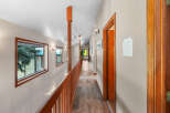 This spacious hallway features a warm wooden railing and a rich wood-paneled floor, creating an inviting atmosphere.