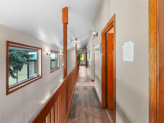 This spacious hallway features a warm wooden railing and a rich wood-paneled floor, creating an inviting atmosphere.