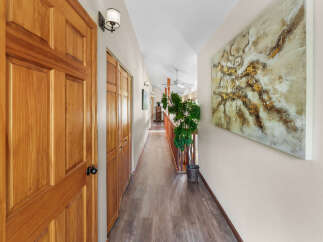 Step into this inviting hallway featuring warm wooden doors and elegant laminate flooring.