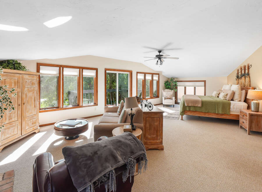 This spacious bedroom suite offers a comfortable living area with a plush sofa and armchairs, perfect for relaxing.