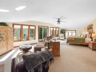 This spacious bedroom suite offers a comfortable living area with a plush sofa and armchairs, perfect for relaxing.