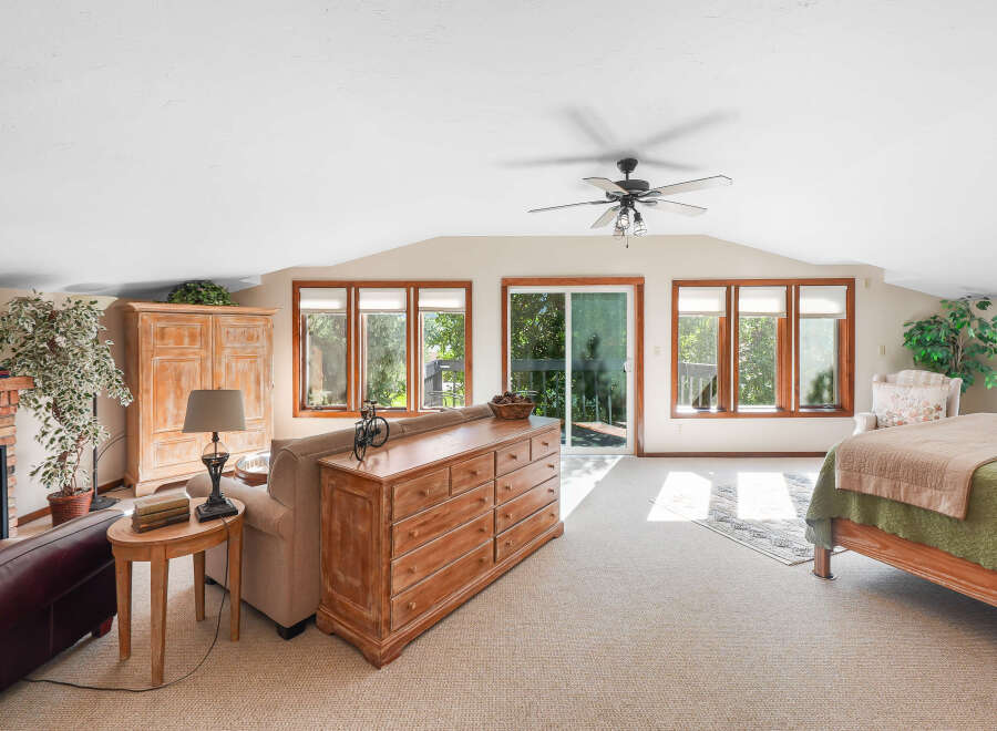 This spacious bedroom offers a comfortable and inviting atmosphere with ample natural light streaming through multiple windows.