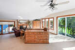Step into this inviting living space featuring a cozy brick fireplace and a large sliding glass door that opens to a scenic deck with lush green views.