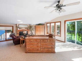 Step into this inviting living space featuring a cozy brick fireplace and a large sliding glass door that opens to a scenic deck with lush green views.