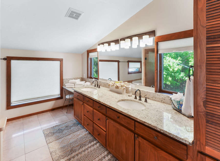 This spacious bathroom boasts a double vanity with granite countertops, offering ample space for morning routines.