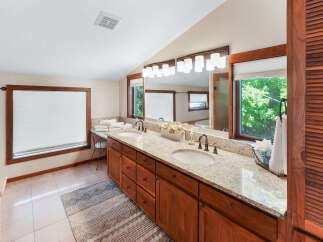 This spacious bathroom boasts a double vanity with granite countertops, offering ample space for morning routines.