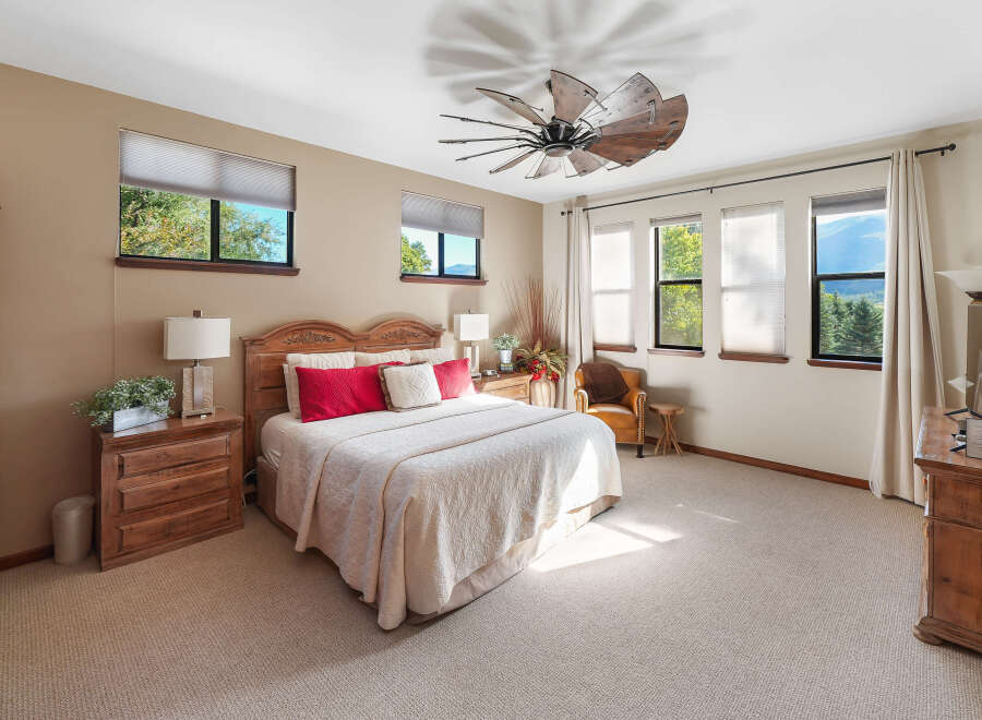 Experience ultimate comfort in this spacious bedroom, featuring a luxurious king-size bed adorned with plush red and white pillows.