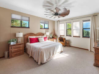 Experience ultimate comfort in this spacious bedroom, featuring a luxurious king-size bed adorned with plush red and white pillows.