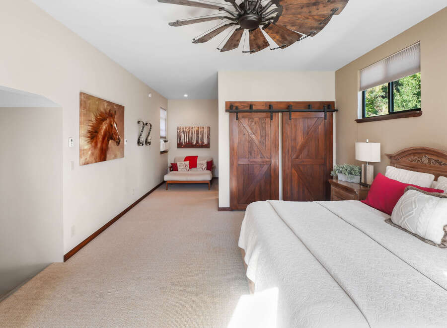 Experience rustic charm in this inviting bedroom, featuring a stunning wooden ceiling fan and elegant barn doors.