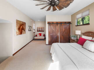 Experience rustic charm in this inviting bedroom, featuring a stunning wooden ceiling fan and elegant barn doors.