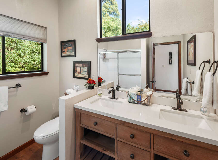 This charming bathroom features a spacious double vanity with a quartz countertop and warm wood cabinetry, complemented by oil-rubbed bronze fixtures.
