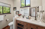 This charming bathroom features a spacious double vanity with a quartz countertop and warm wood cabinetry, complemented by oil-rubbed bronze fixtures.