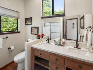 This charming bathroom features a spacious double vanity with a quartz countertop and warm wood cabinetry, complemented by oil-rubbed bronze fixtures.