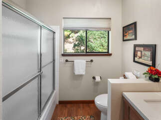 This bathroom offers a refreshing retreat with a frosted glass shower door and a large window overlooking lush greenery.