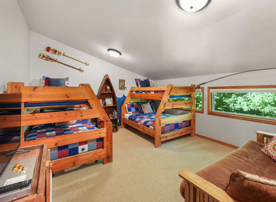 This charming attic bedroom features two sturdy wooden bunk beds with patriotic bedding, perfect for accommodating multiple guests.
