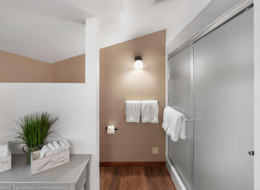 This bathroom features a modern shower with frosted glass doors and a sleek chrome handle.