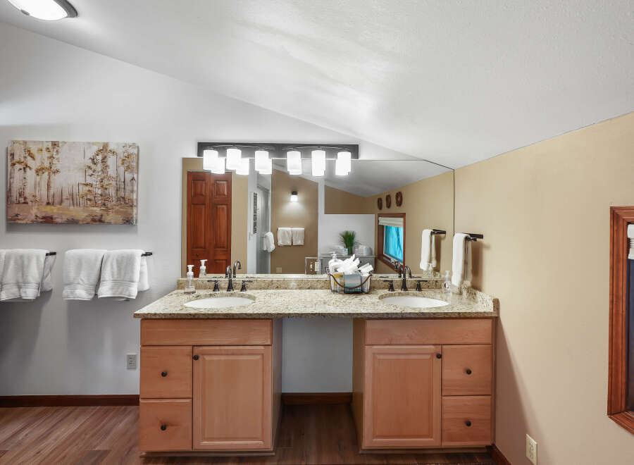 This spacious bathroom features a double vanity with granite countertops and ample storage.