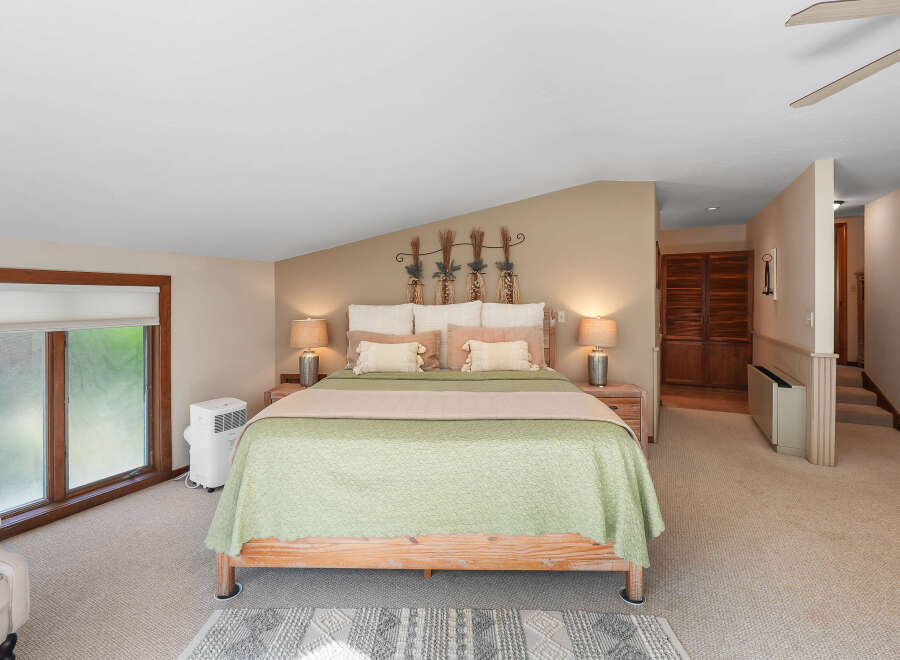 Discover this charming bedroom featuring a comfortable queen-size bed adorned with a light green quilted comforter and accent pillows.