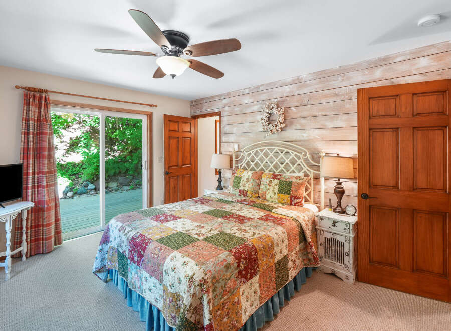 Step into this charming bedroom featuring a cozy queen-size bed adorned with a beautiful patchwork quilt.