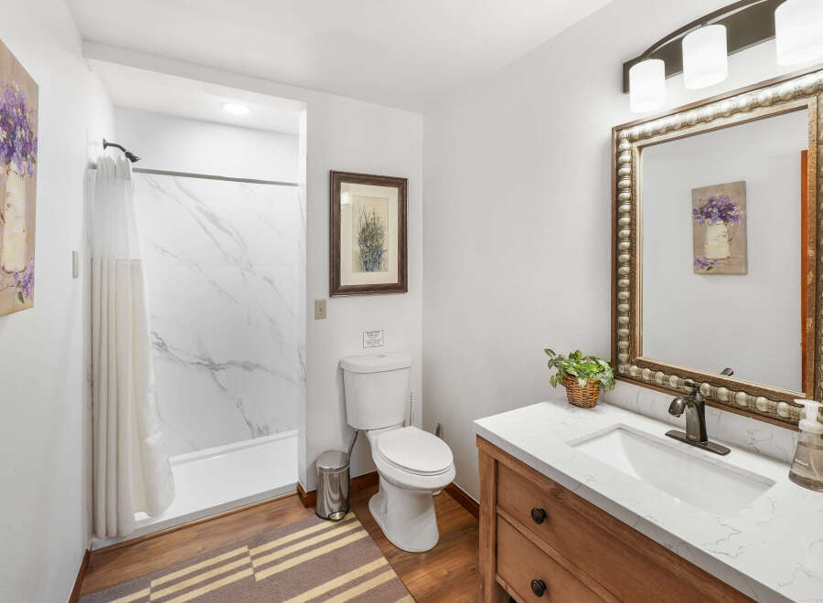 This charming bathroom features a clean white toilet and a sleek shower with marble-patterned walls.