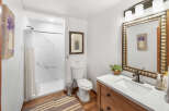 This charming bathroom features a clean white toilet and a sleek shower with marble-patterned walls.