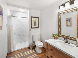 This charming bathroom features a clean white toilet and a sleek shower with marble-patterned walls.