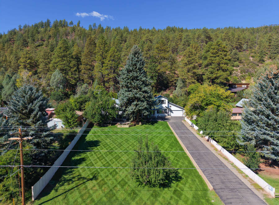 Nestled amidst a lush forest, this stunning property offers a serene retreat with a beautifully manicured lawn featuring a diamond pattern.