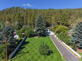 Nestled amidst a lush forest, this stunning property offers a serene retreat with a beautifully manicured lawn featuring a diamond pattern.