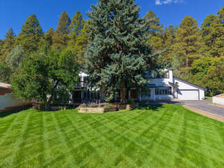 Nestled amidst a backdrop of mature pine trees and lush greenery, this stunning property offers a serene retreat.