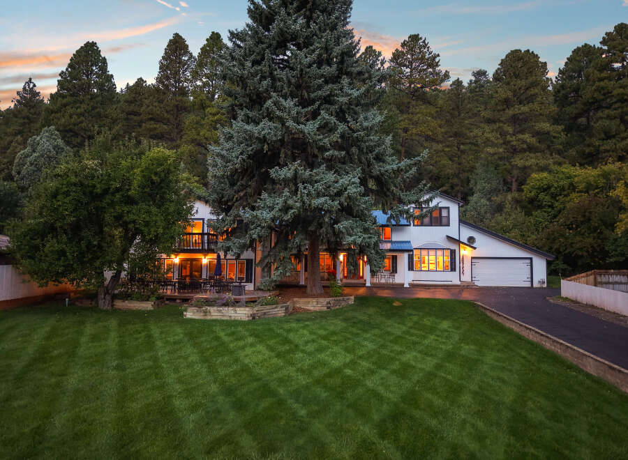 Nestled amidst a serene forest backdrop, this stunning white home offers a perfect blend of modern comfort and natural beauty.