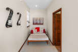 This hallway features a cozy seating area with a light-colored daybed adorned with red and patterned throw pillows, and a red throw blanket.
