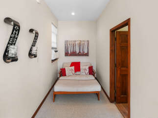 This hallway features a cozy seating area with a light-colored daybed adorned with red and patterned throw pillows, and a red throw blanket.