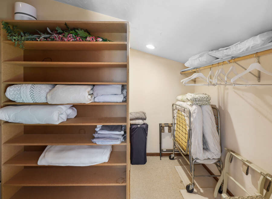 This spacious closet offers ample storage with its multi-tiered shelving unit, perfect for organizing linens and bedding.