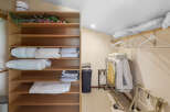 This spacious closet offers ample storage with its multi-tiered shelving unit, perfect for organizing linens and bedding.