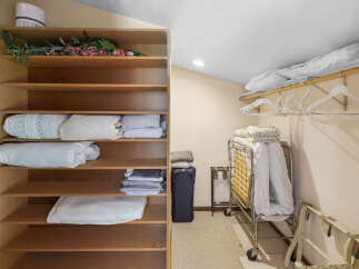 This spacious closet offers ample storage with its multi-tiered shelving unit, perfect for organizing linens and bedding.