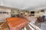 This spacious living area features a large, covered table perfect for games or dining, complemented by comfortable seating arrangements including plush sofas and an armchair.