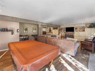 This spacious living area features a large, covered table perfect for games or dining, complemented by comfortable seating arrangements including plush sofas and an armchair.