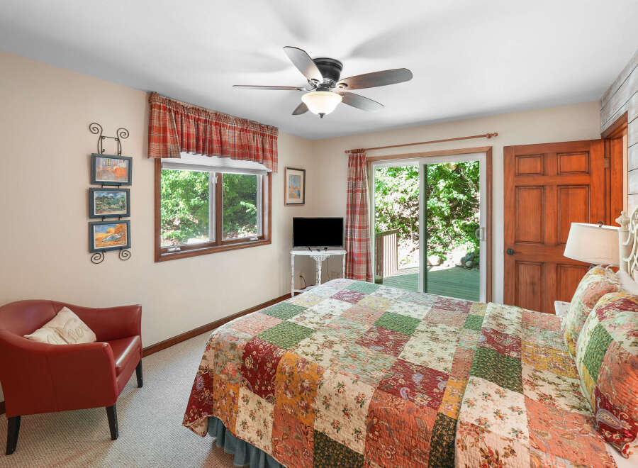 This charming bedroom features a cozy red armchair and a queen-sized bed adorned with a beautiful patchwork quilt.