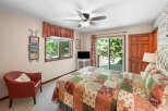 This charming bedroom features a cozy red armchair and a queen-sized bed adorned with a beautiful patchwork quilt.