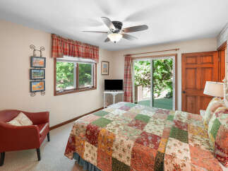 This charming bedroom features a cozy red armchair and a queen-sized bed adorned with a beautiful patchwork quilt.