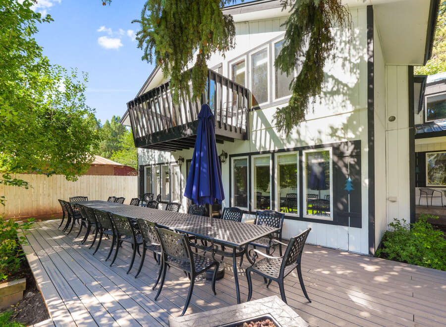 Enjoy outdoor dining and entertaining on this expansive deck, featuring a long table set for many guests and comfortable seating.