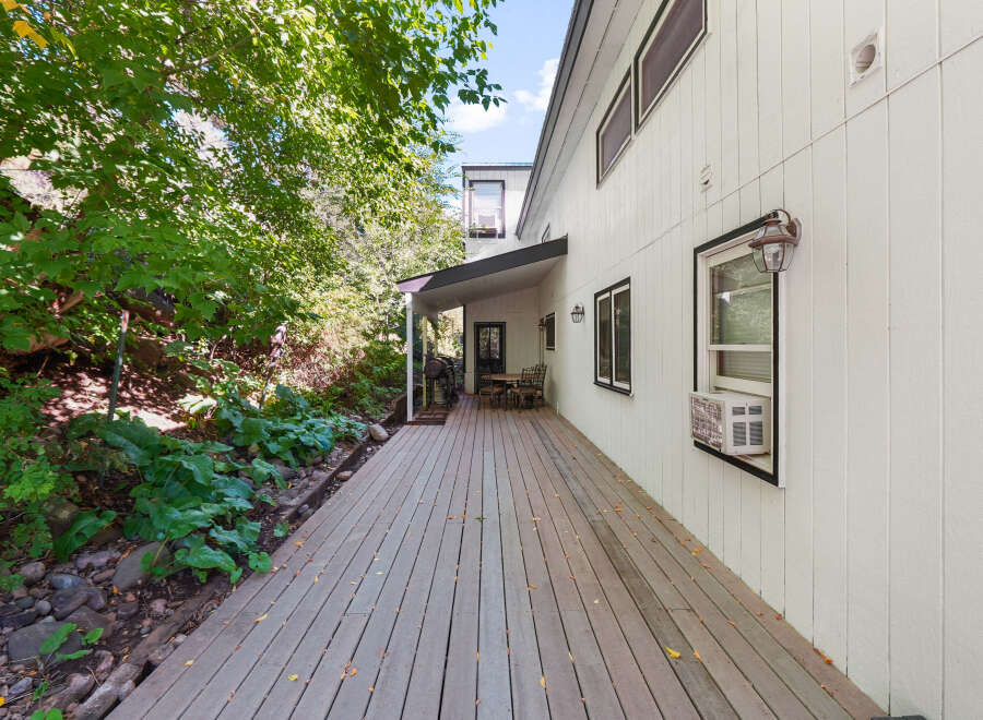 Enjoy outdoor living on this expansive wooden deck, perfect for entertaining or relaxing amidst lush greenery.
