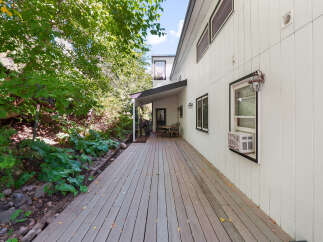 Enjoy outdoor living on this expansive wooden deck, perfect for entertaining or relaxing amidst lush greenery.