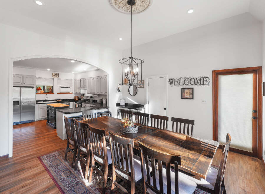 This spacious dining area features a large, rustic wooden table with seating for eight, perfect for family gatherings and entertaining.