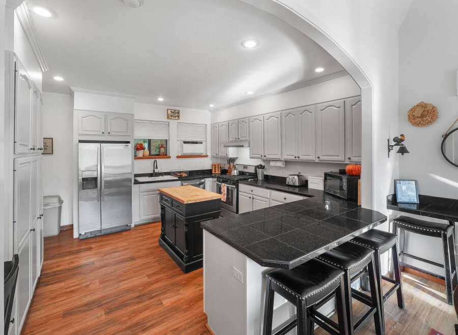 This spacious kitchen boasts elegant gray cabinetry and sleek black granite countertops, perfect for any home chef.